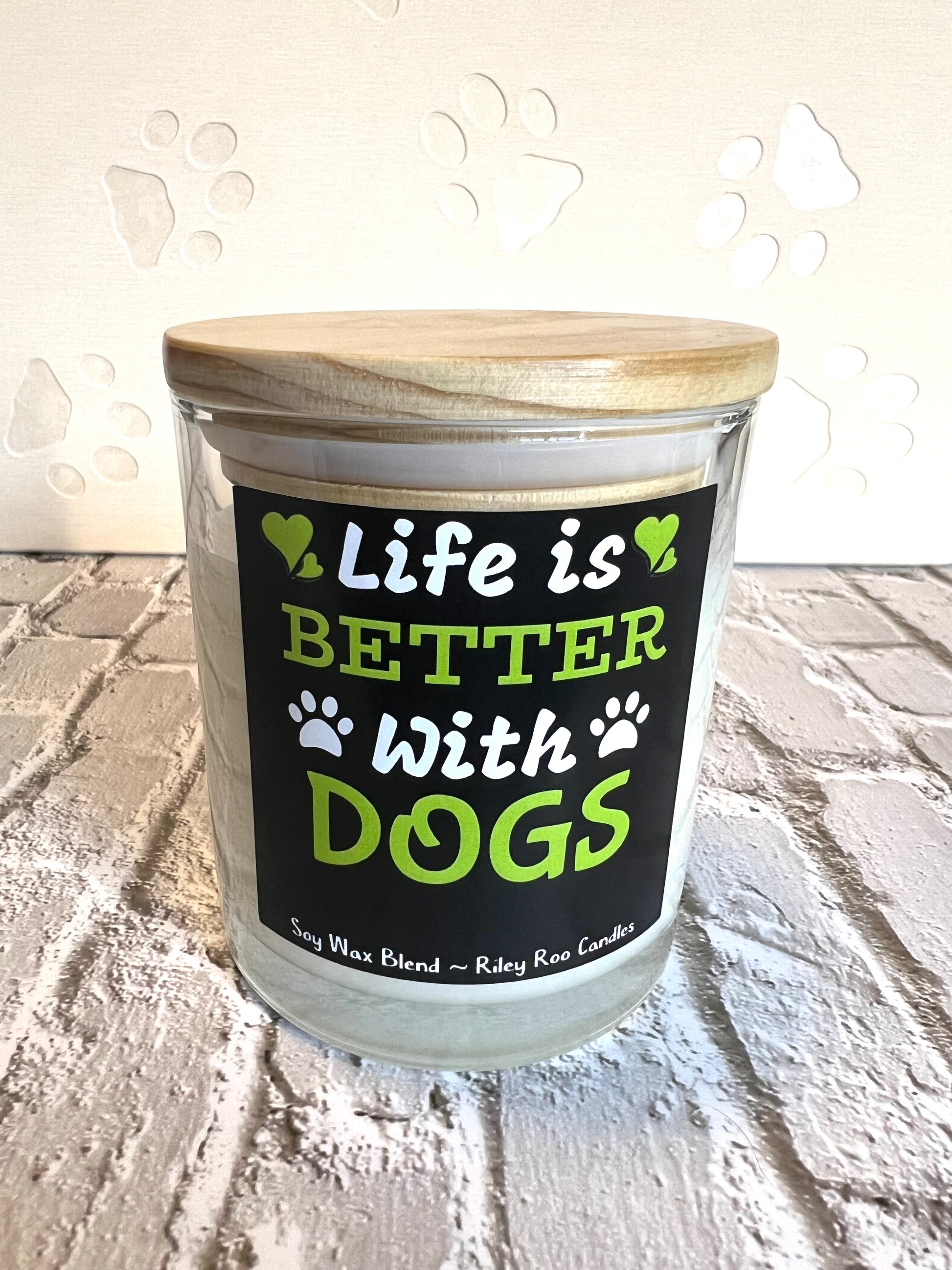 Candle with a wooden lid and 'Life is Better with Dogs' label on a textured surface.